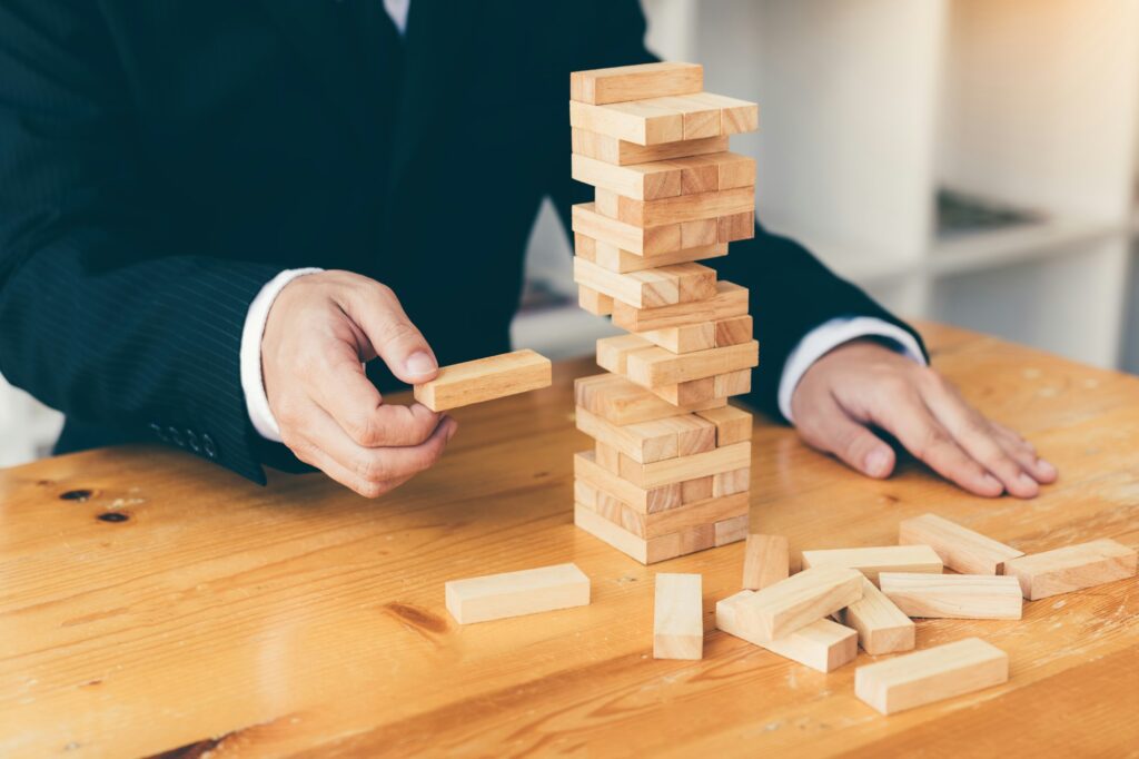 Strategic thinking and risk by business people pulls wooden blocks from the group.